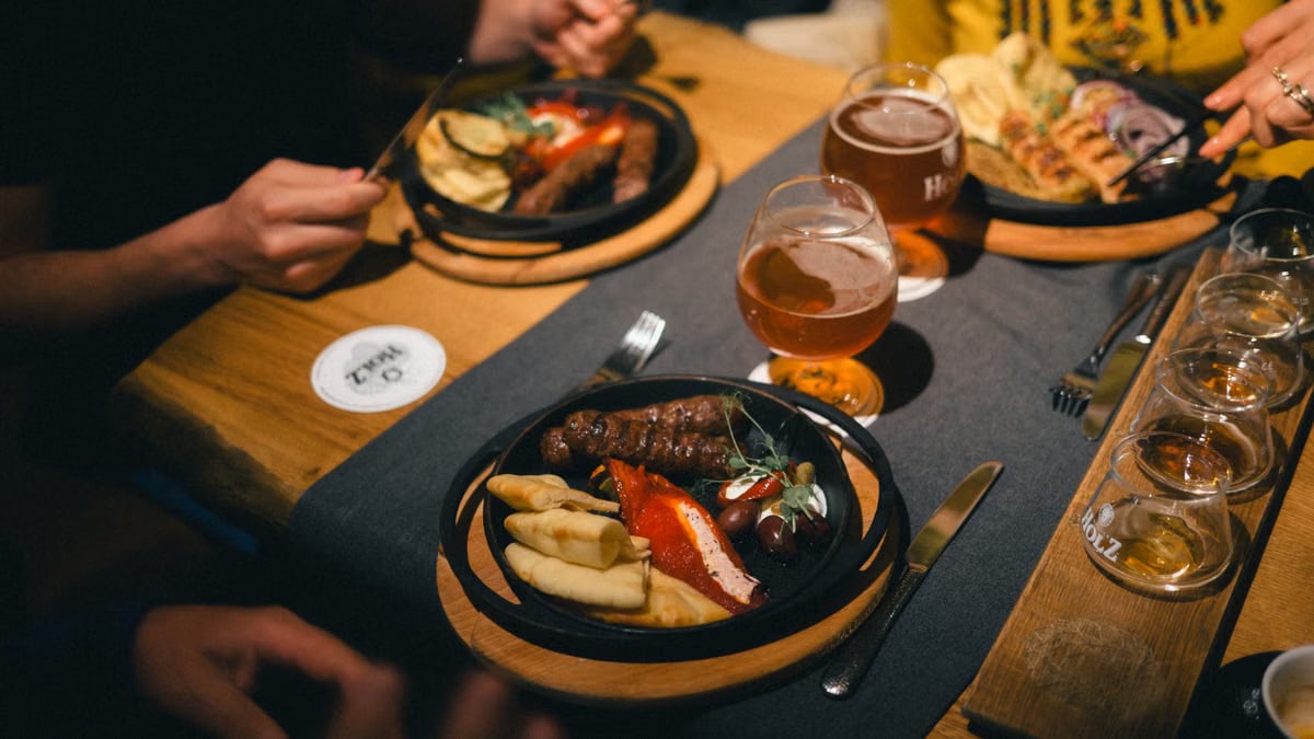 Friends enjoying a casual meal with beer and diverse platters in a cozy setting.